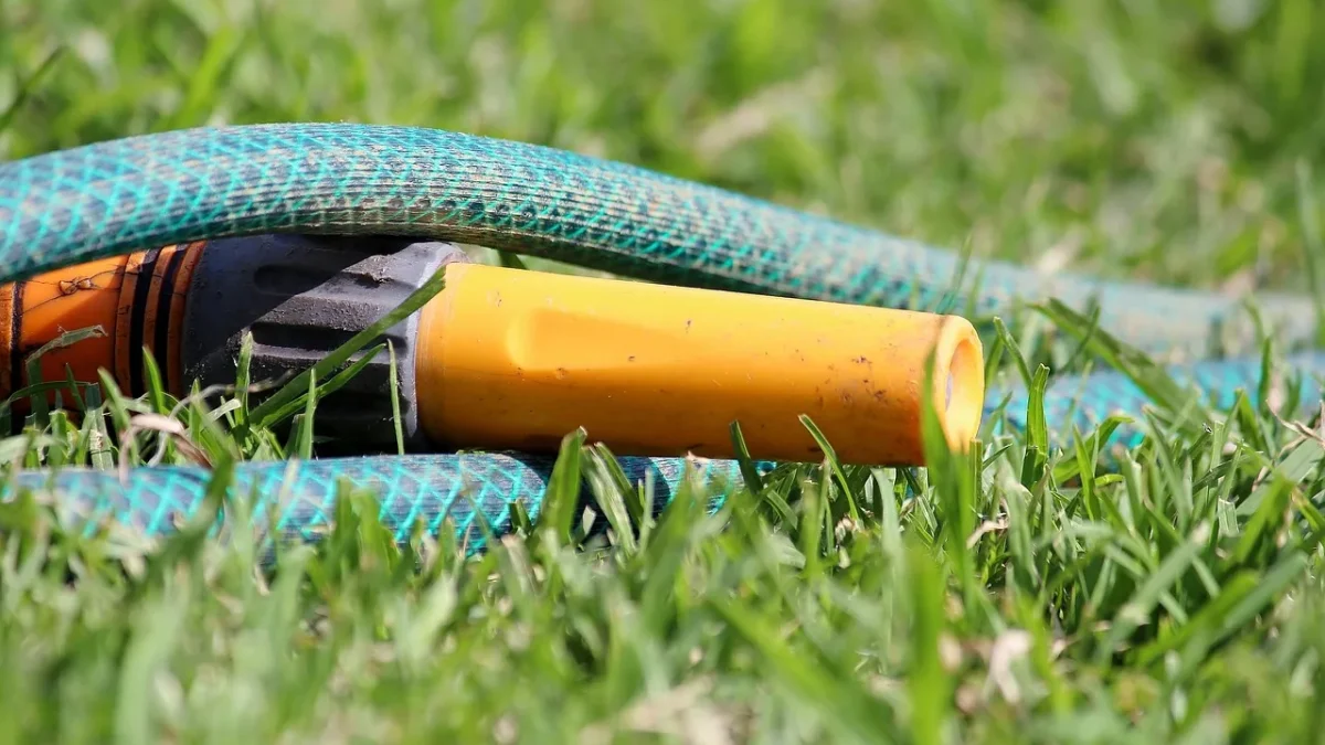 A digital battery-powered hose timer with a display connected to a drip irrigation line