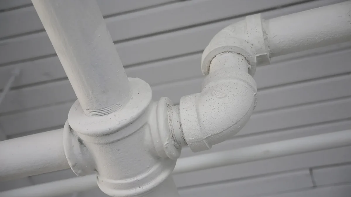 Hands pushing 1/2 inch drip tubing onto a barbed tee fitting in a garden