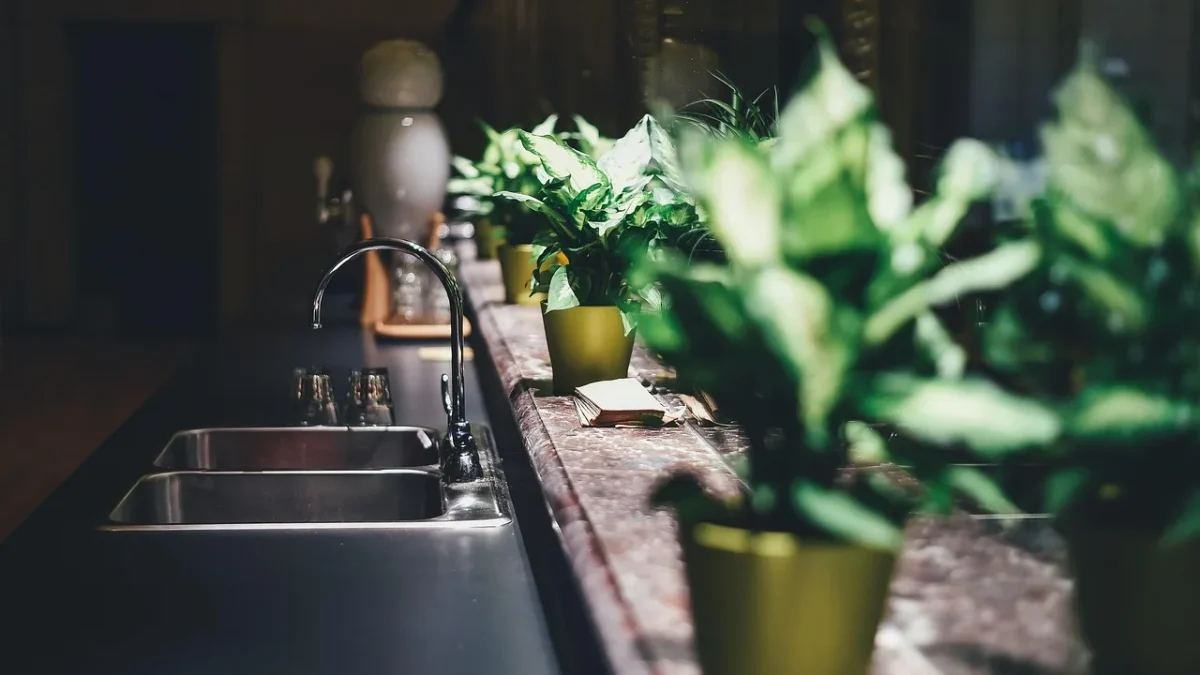 Battery drip timer attached to an outdoor faucet with tubing running to a garden bed