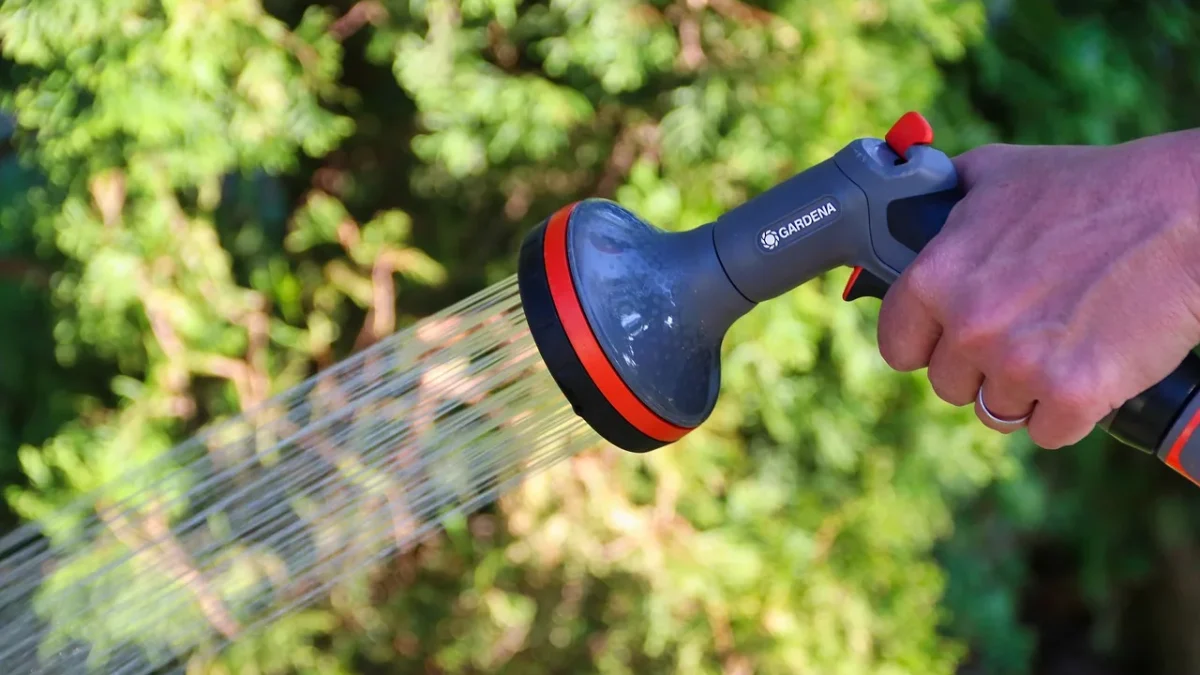 A wifi drip timer mounted on an outdoor hose bib with a smartphone app open beside it